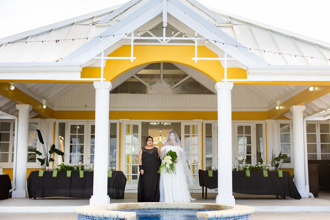 Modern white and yellow wedding venue with colonial-style architecture and covered patio.