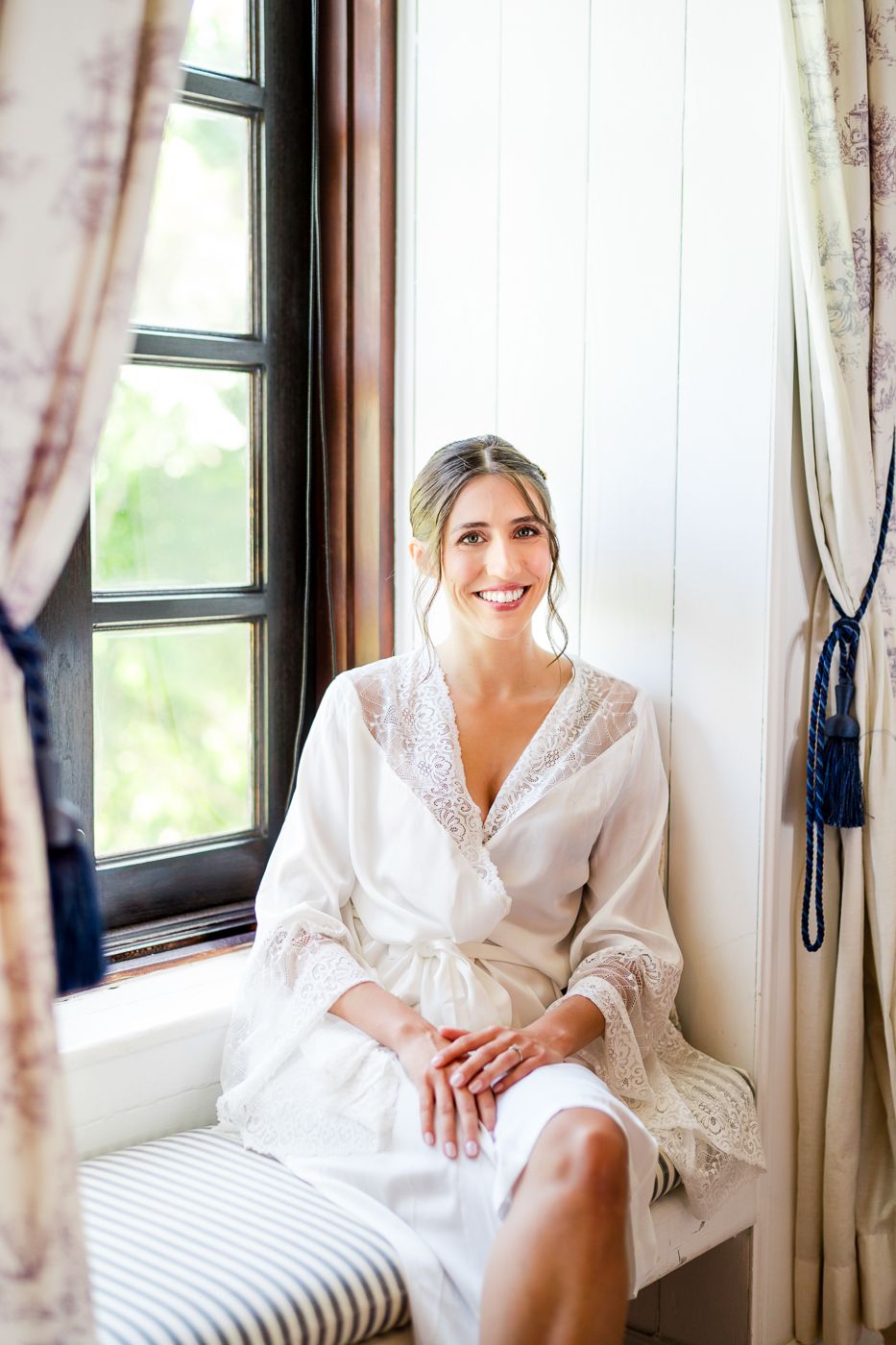 Wedding preparation scene by a window with soft natural light and white lace robe.