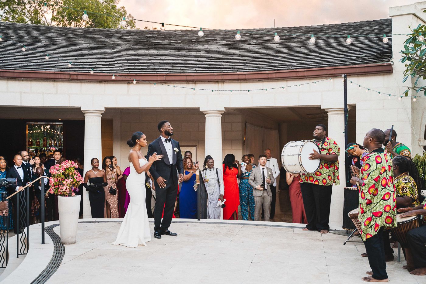 Wedding reception gathering under covered outdoor patio with string lights.