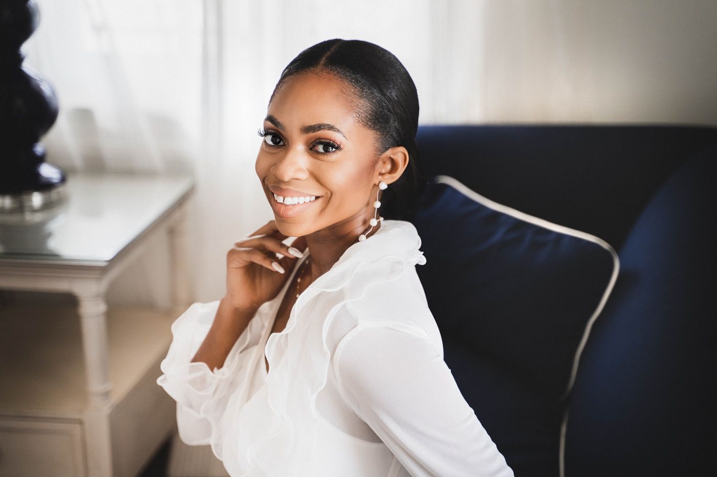 A side profile portrait of someone in a white top against a neutral background.