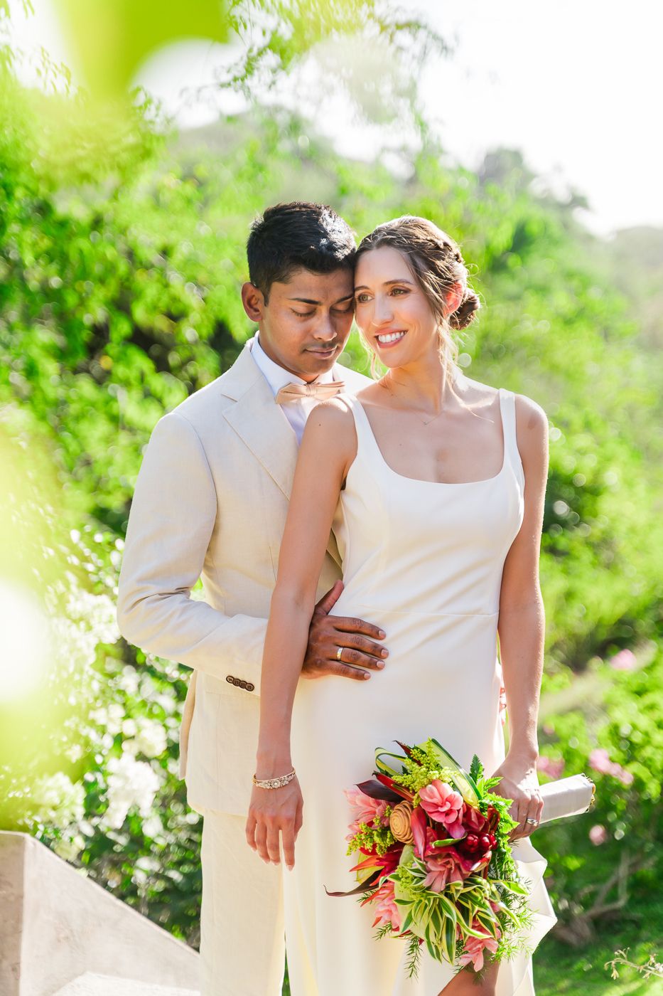 Tropical wedding photos capturing intimate moments between a couple surrounded by lush greenery.