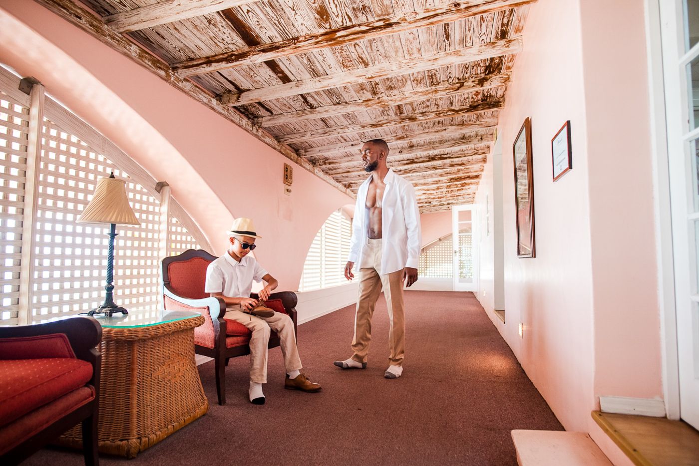 Pink-toned hallway with vintage decor and natural lighting streaming through windows.