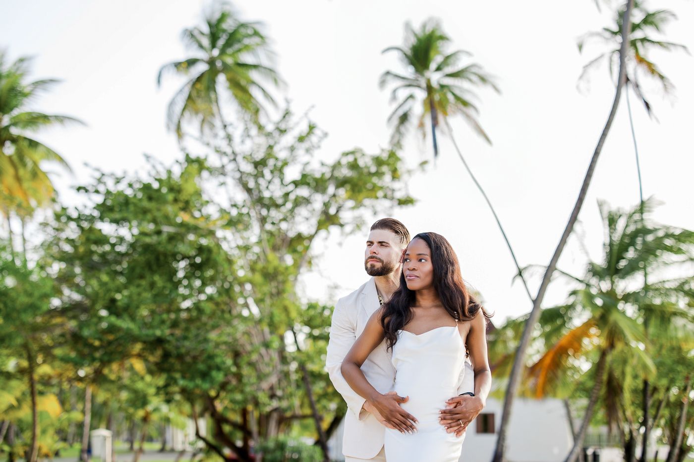 A group of wedding portraits featuring elegant couples posing among tropical palm trees and greenery on a beach.
