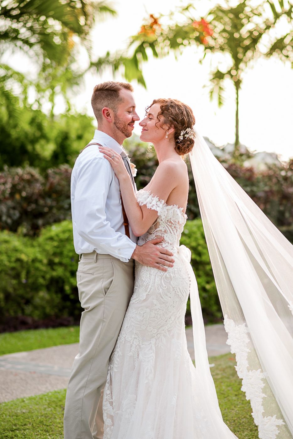 Romantic garden wedding portraits with flowing veil and lush tropical greenery.