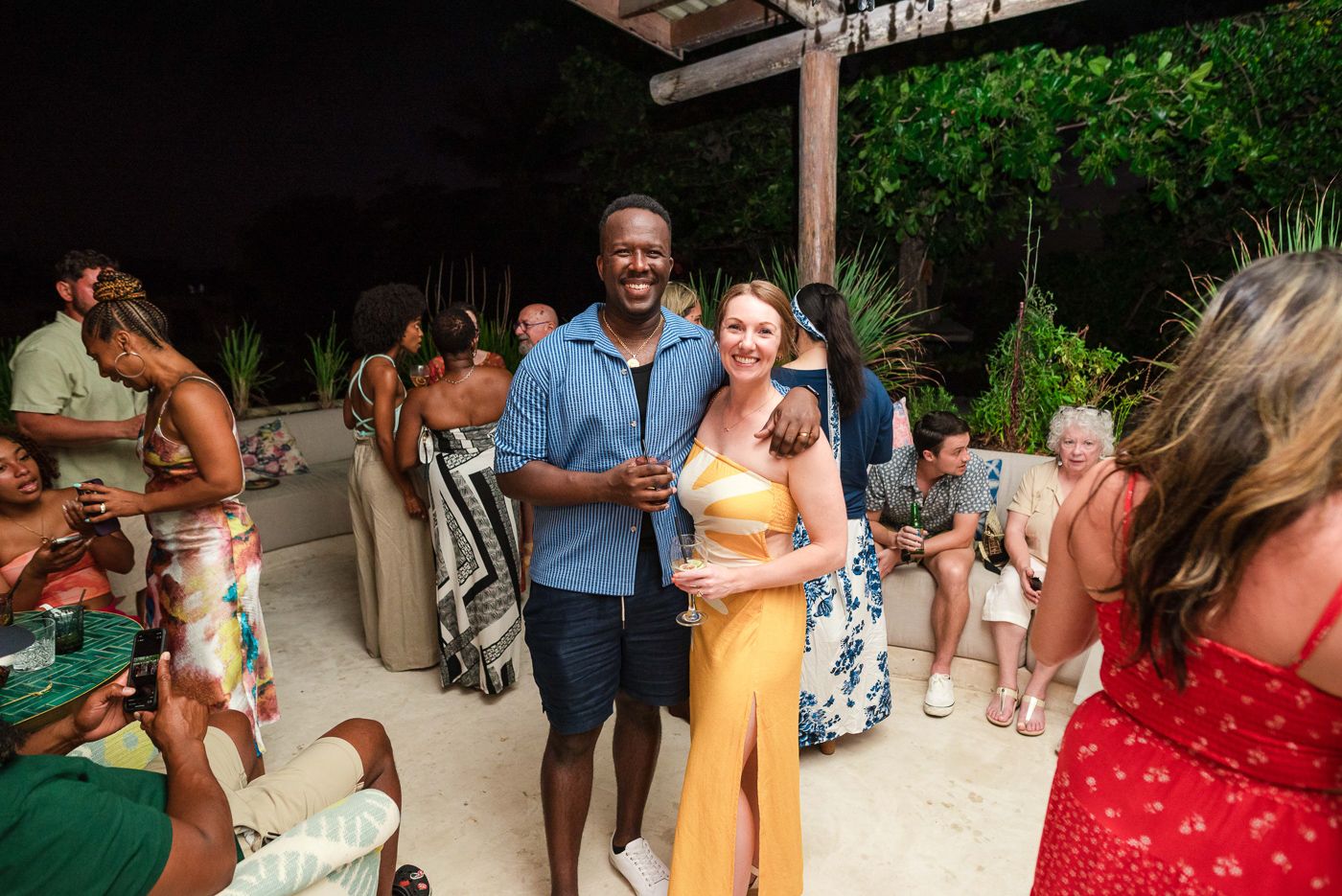 Party guests mingling at an outdoor social gathering wearing colorful summer outfits.