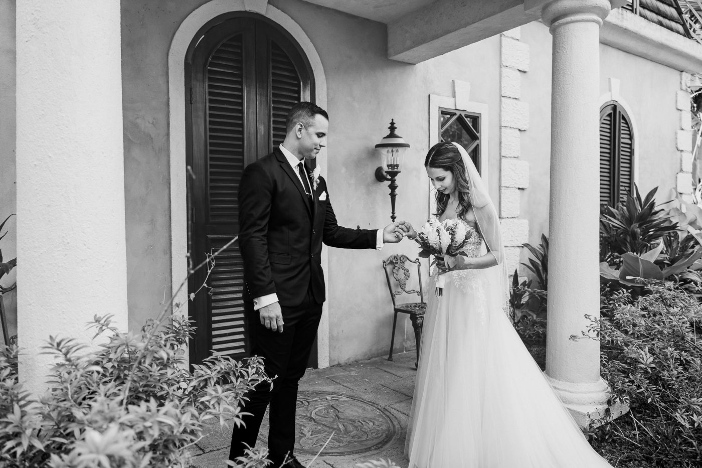 Black and white photo of bride and groom sharing a first look moment outside an elegant villa.
