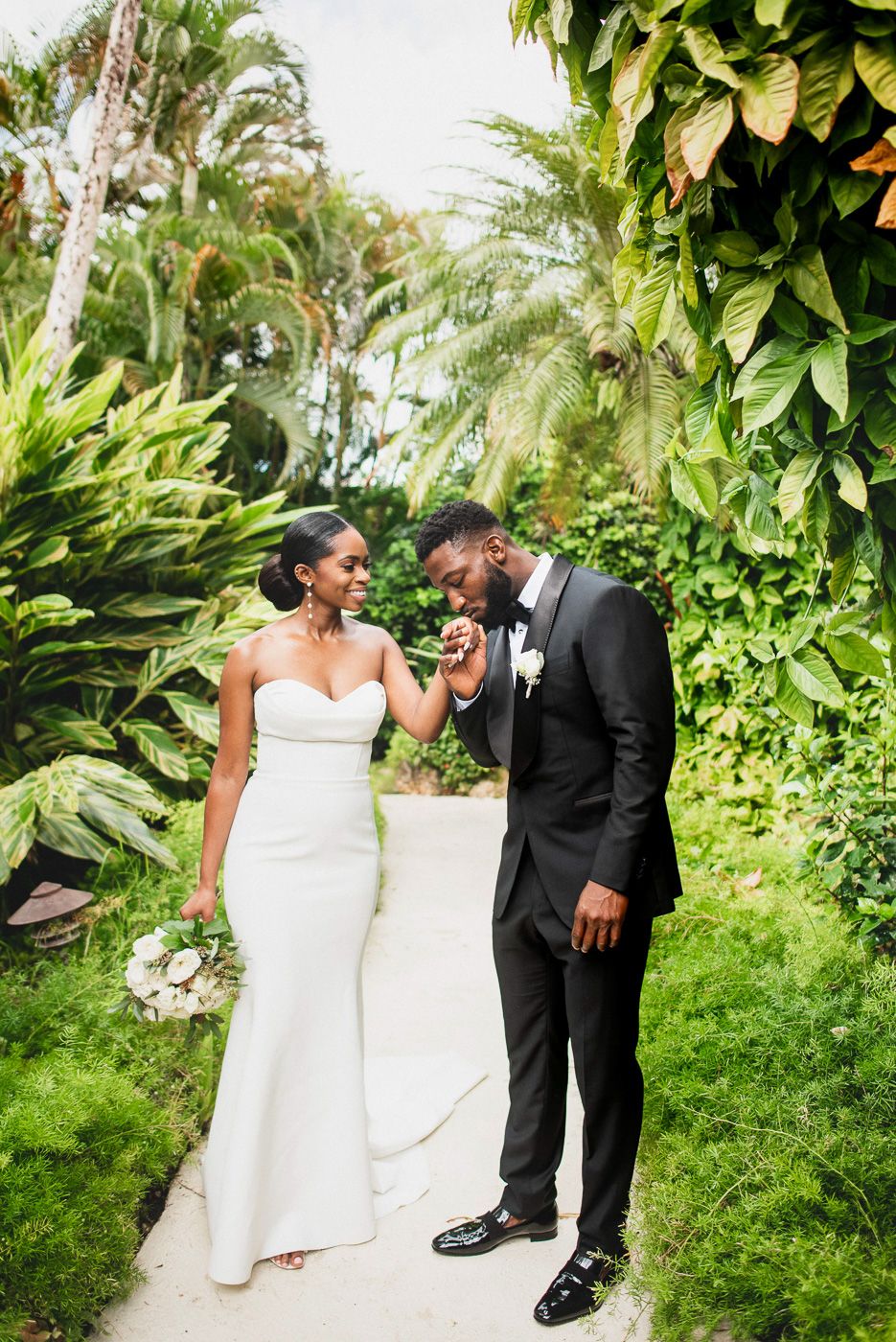 Romantic wedding portrait on garden path surrounded by tropical foliage.