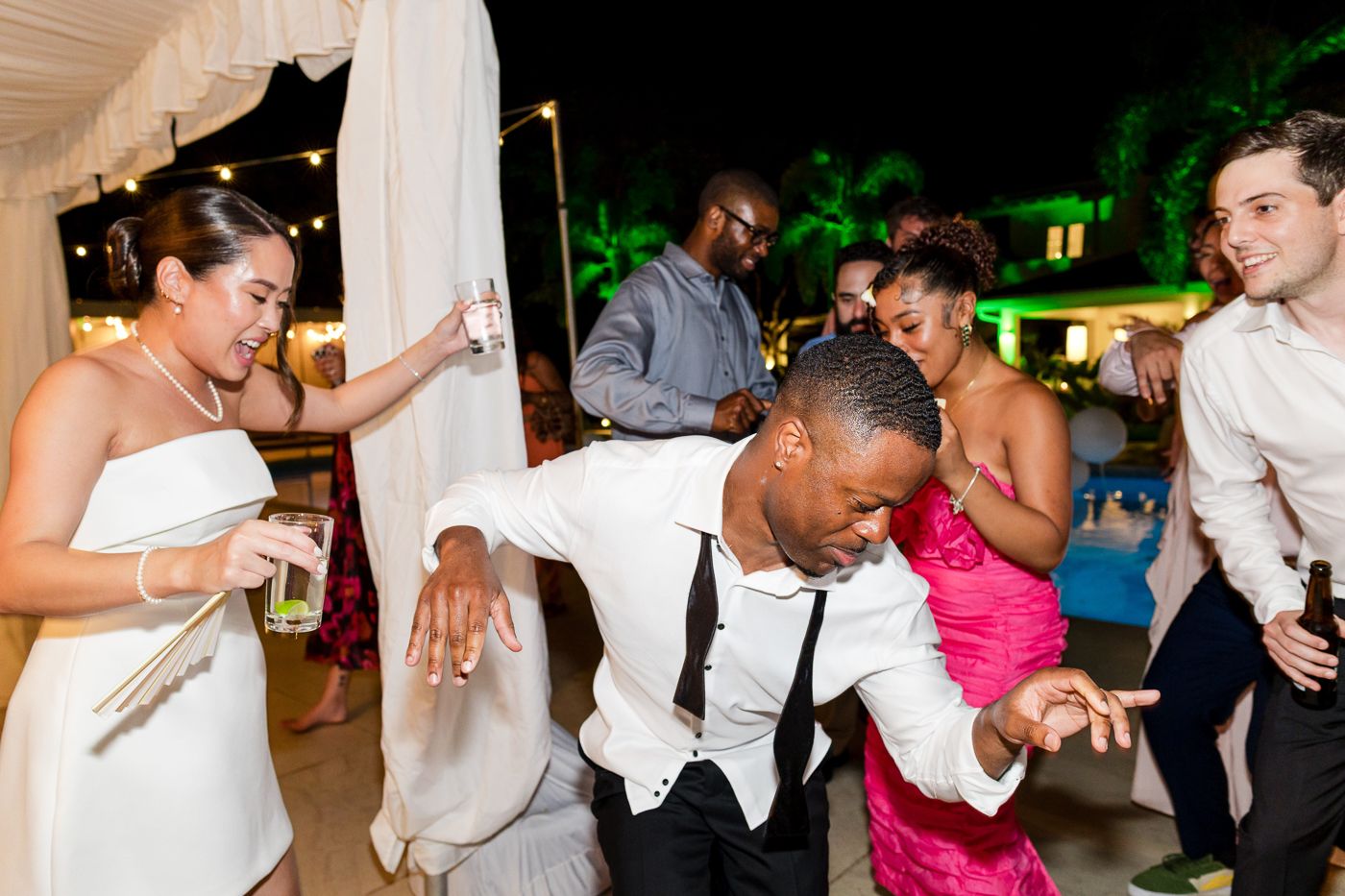 Lively dancing and celebration shots from a wedding reception under an outdoor tent.