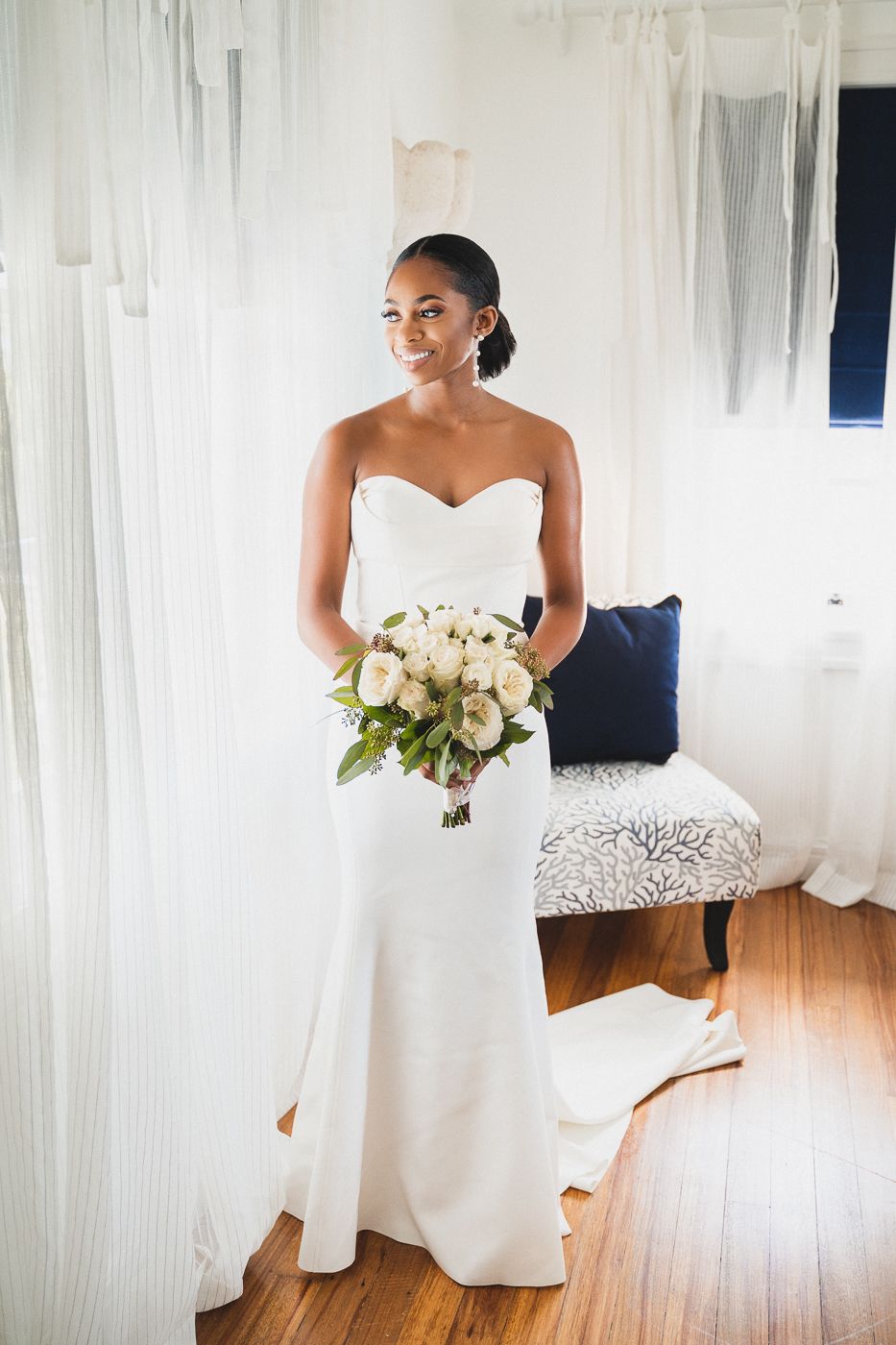 Elegant wedding portrait with white bouquet against draped fabric background.