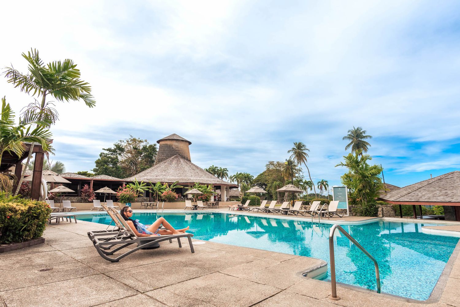 Panoramic view of resort swimming pool with palm trees and ocean views.