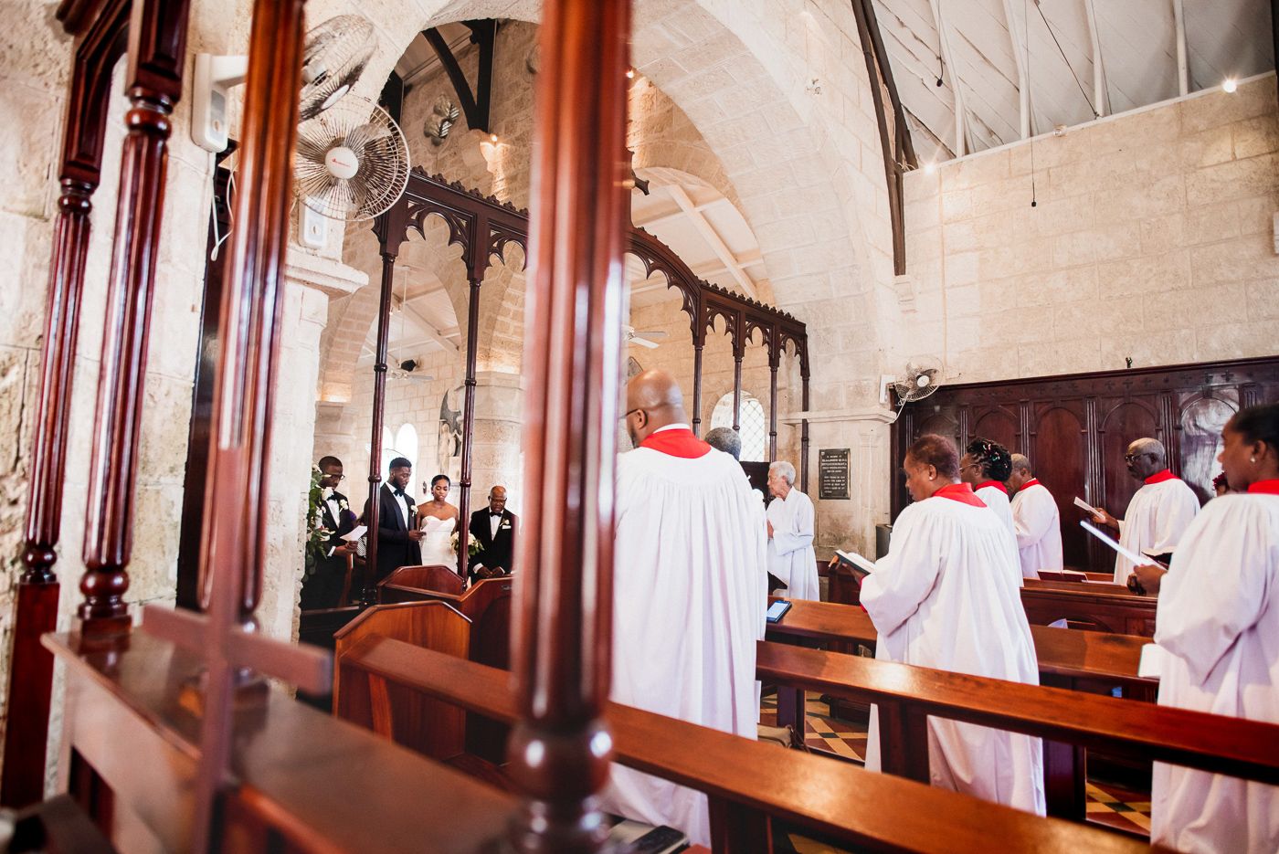 Church interior with wooden pews and clergy in red and white robes during ceremony.