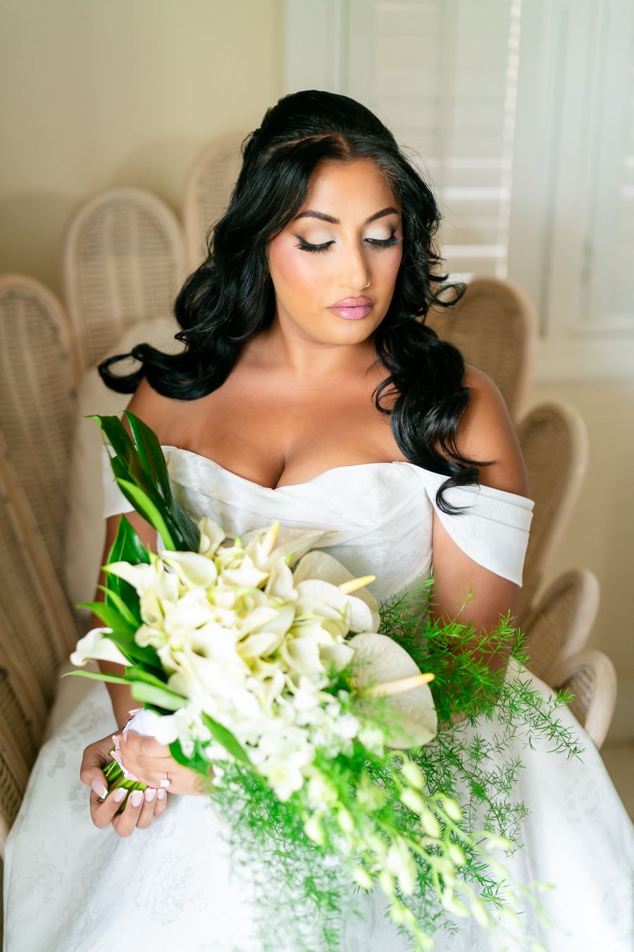 Elegant bridal portrait with cascading white and green bouquet in natural window light.
