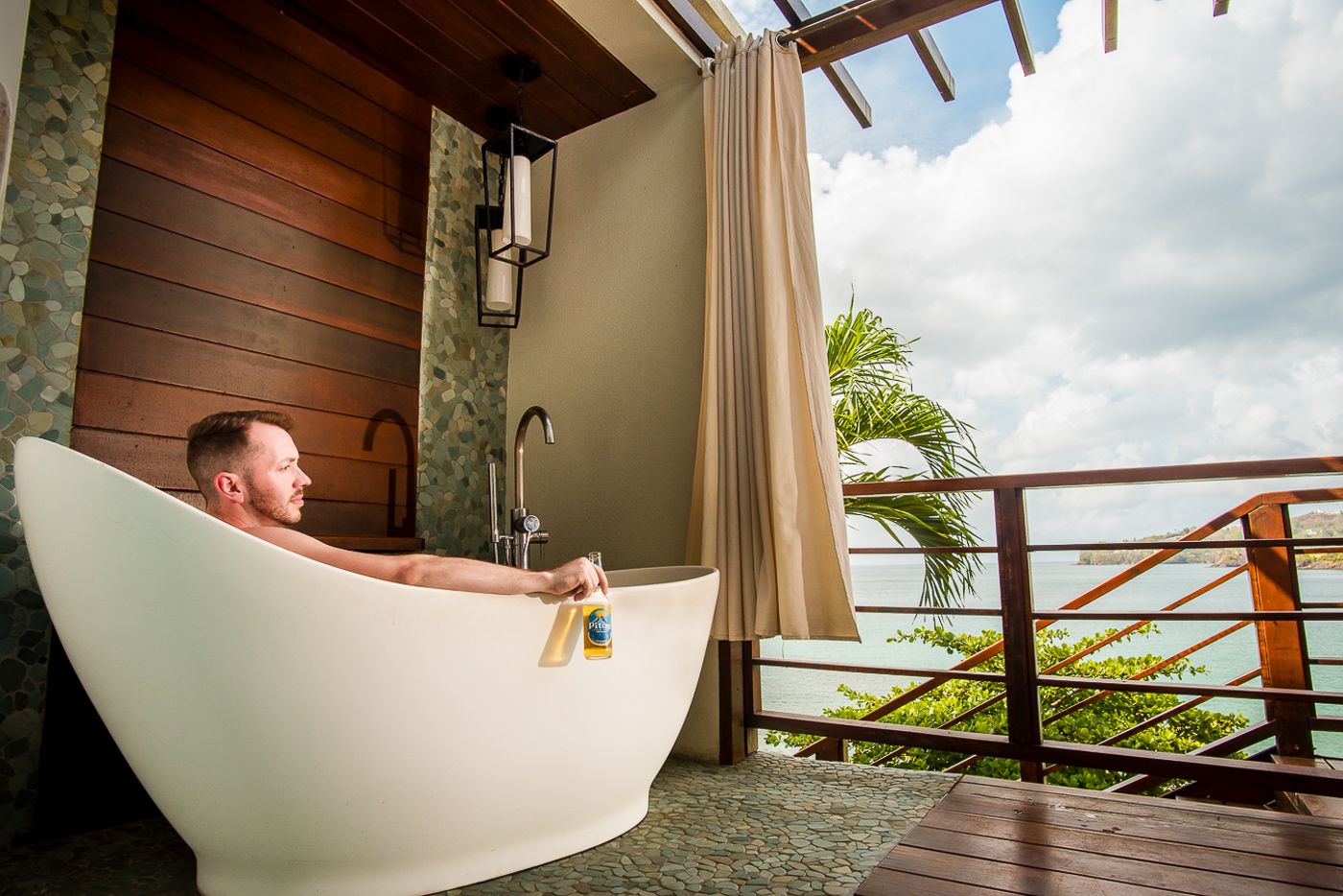 Modern bathroom interior with freestanding tub and outdoor tropical views.