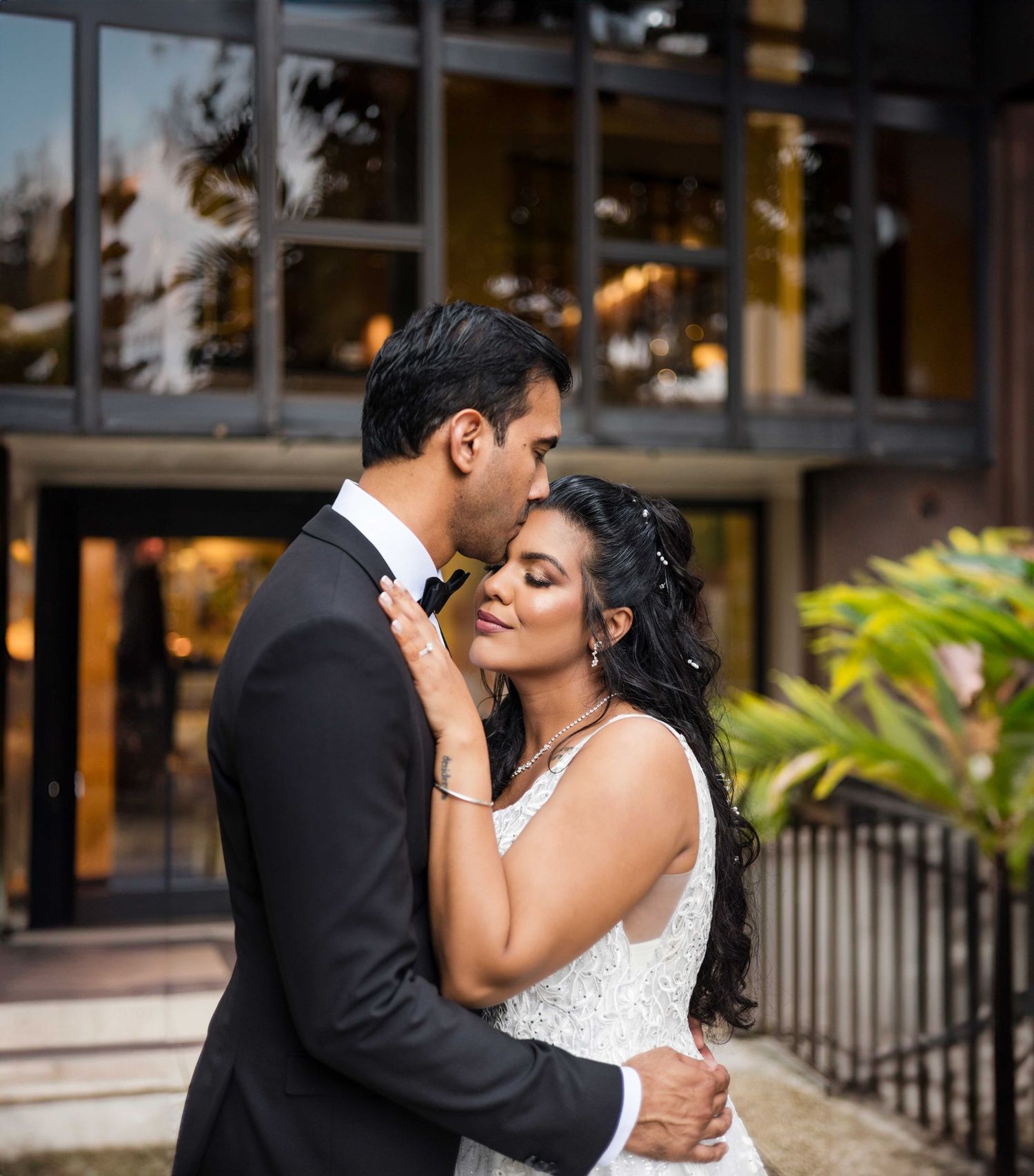 Romantic wedding moment captured at sunset outside a modern venue.