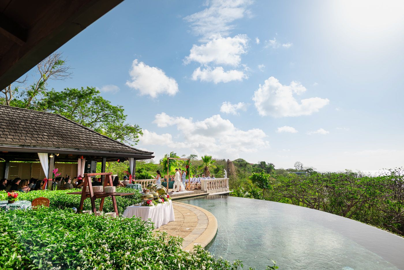 Luxury resort pool and lounge area surrounded by lush tropical landscaping.