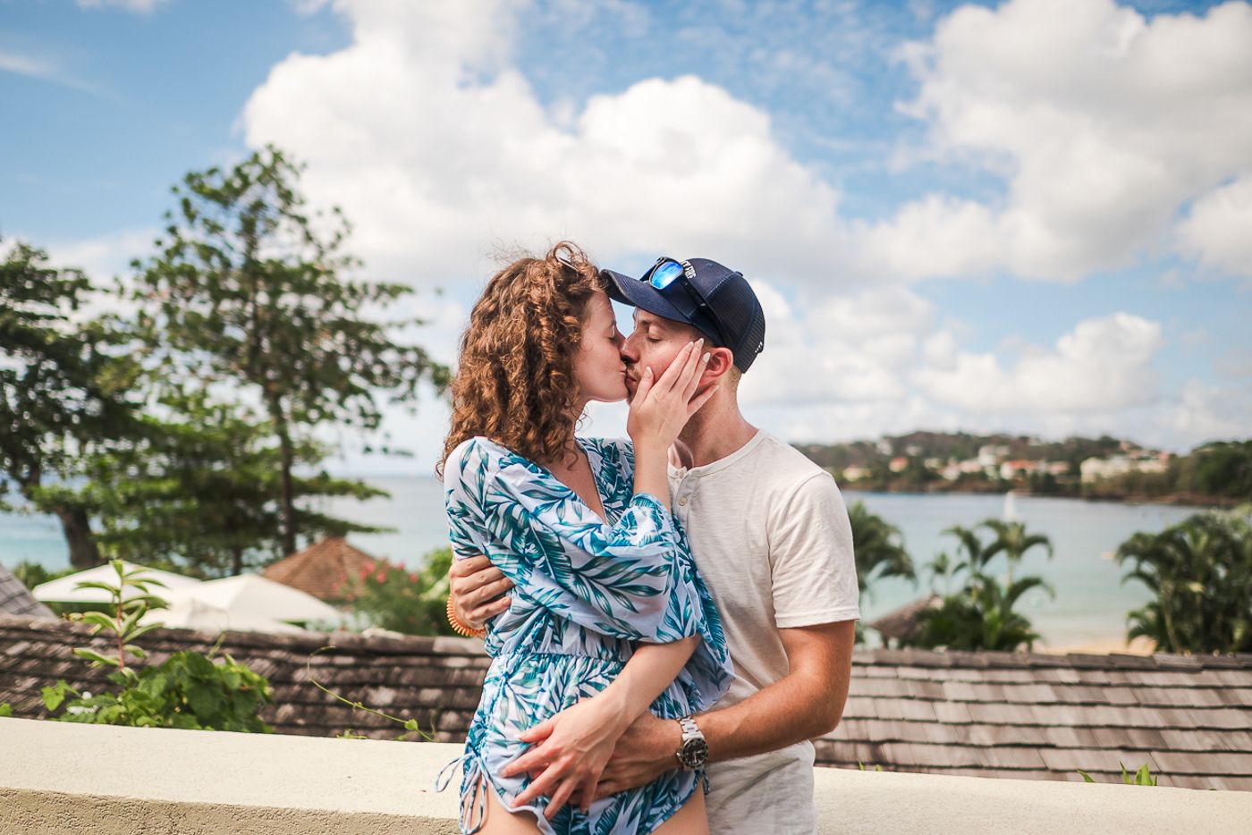 A romantic embrace overlooking a tropical bay with palm trees and blue skies in the background.