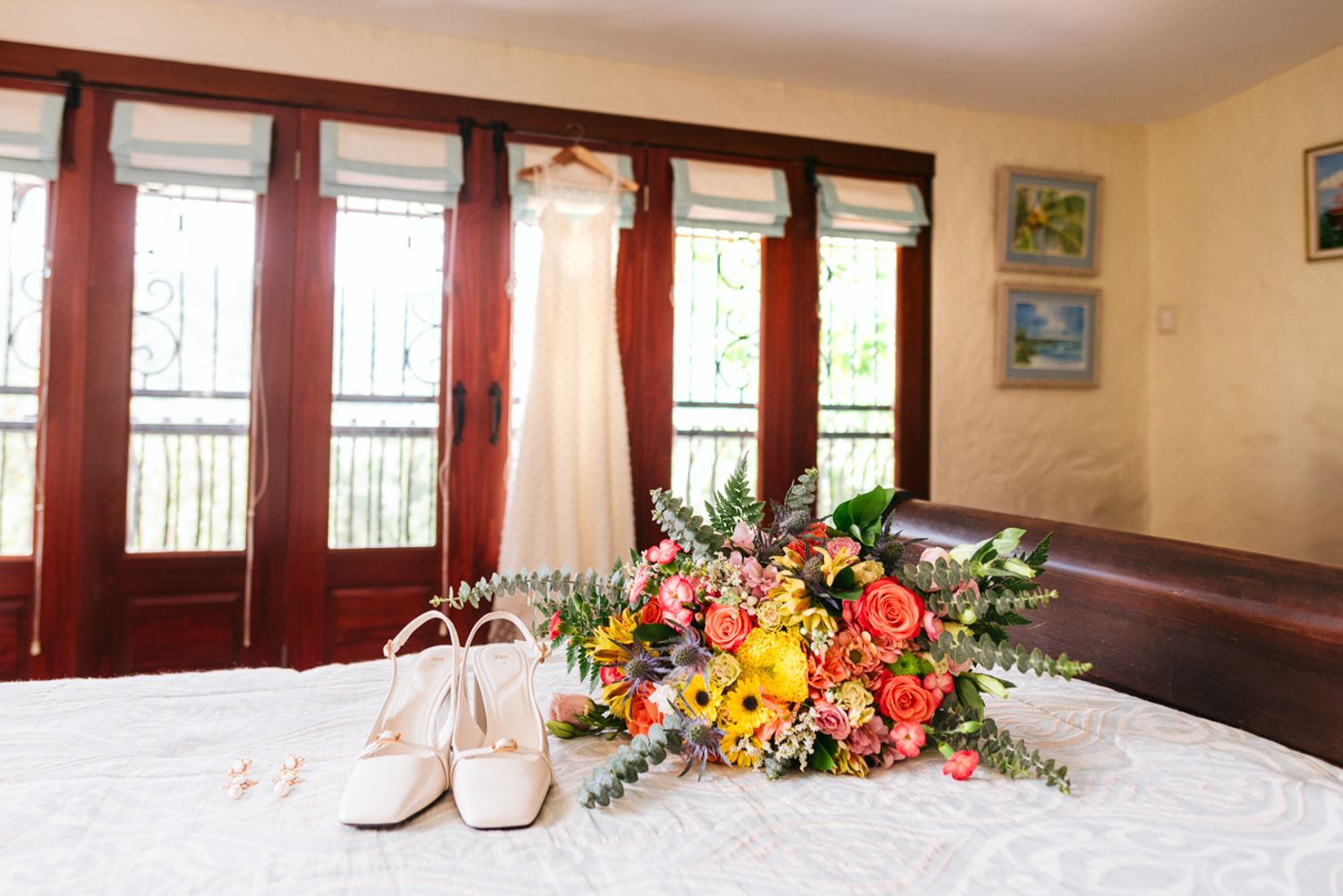 An elegant wedding reception banquet hall with cream walls, red curtains, and floral centerpieces on tables.