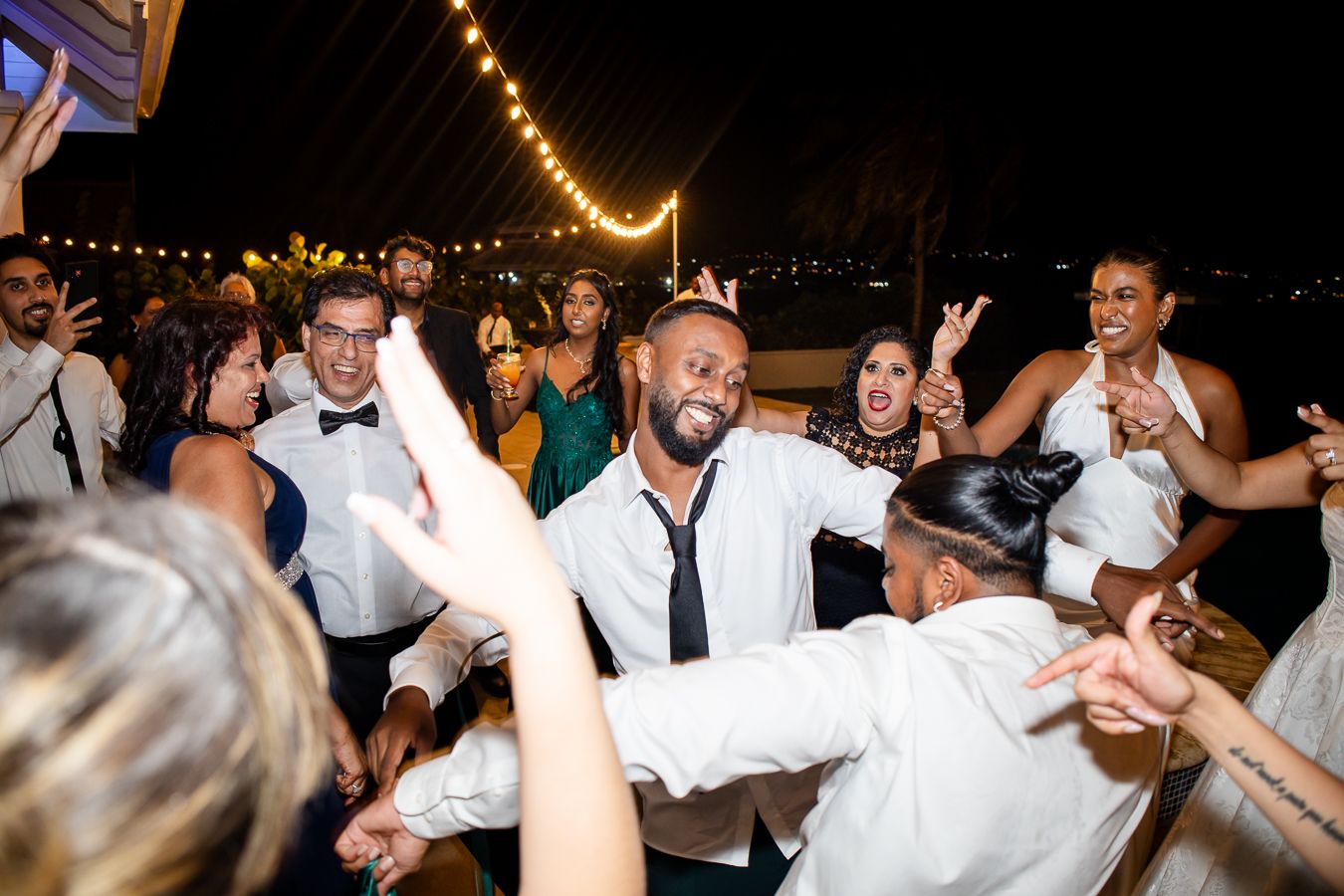 Lively dance floor celebration with guests during nighttime wedding reception.