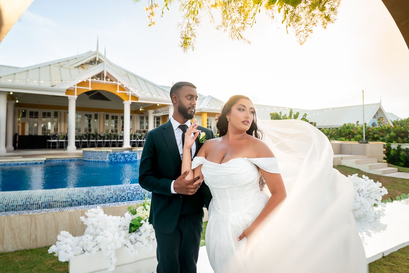 Wedding couple poses for romantic portraits at an elegant outdoor venue with pool and palm trees.