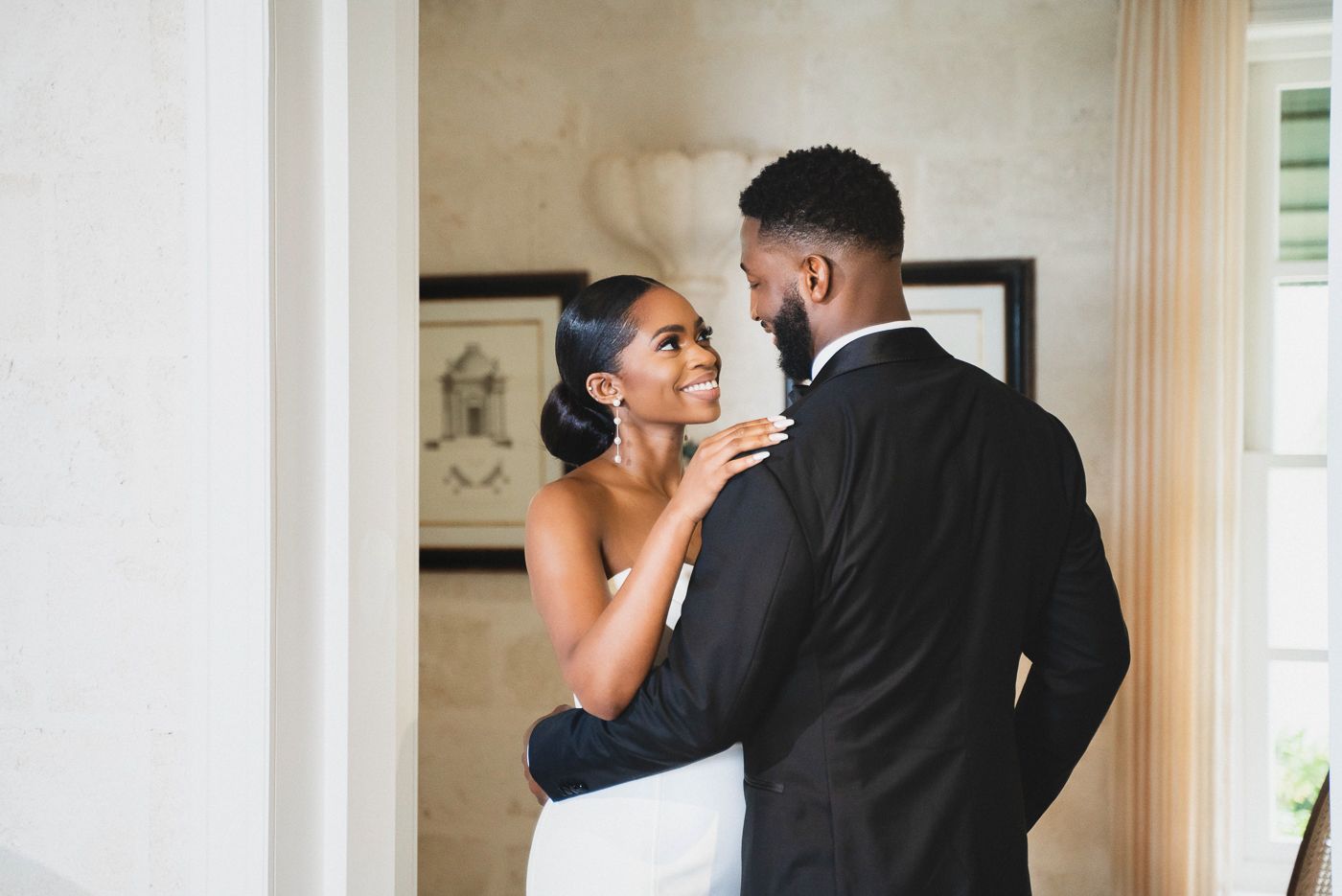A tender moment between newlyweds sharing an intimate embrace against a light colored wall.