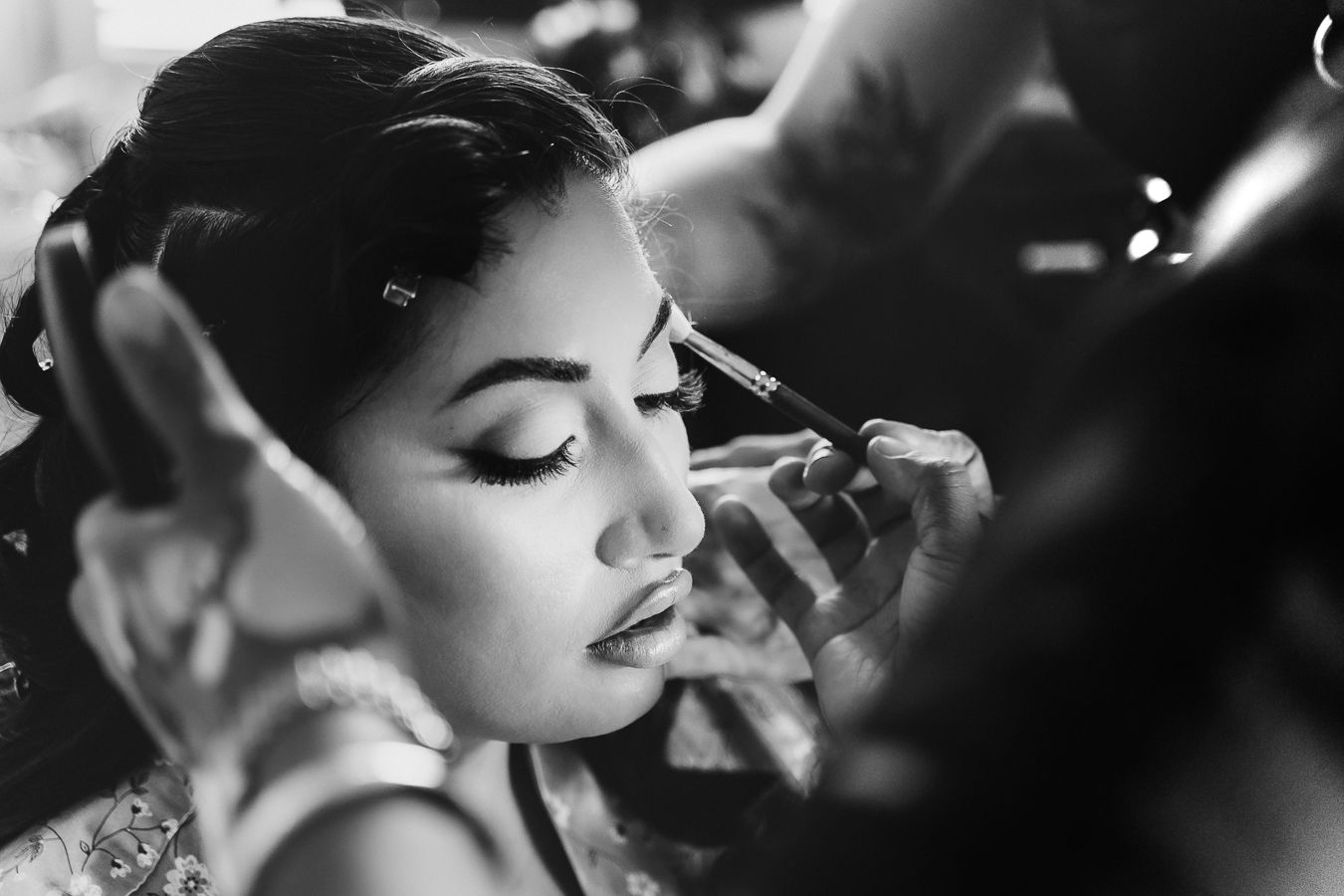 Wedding preparation photos in black and white showing makeup application and getting ready moments.