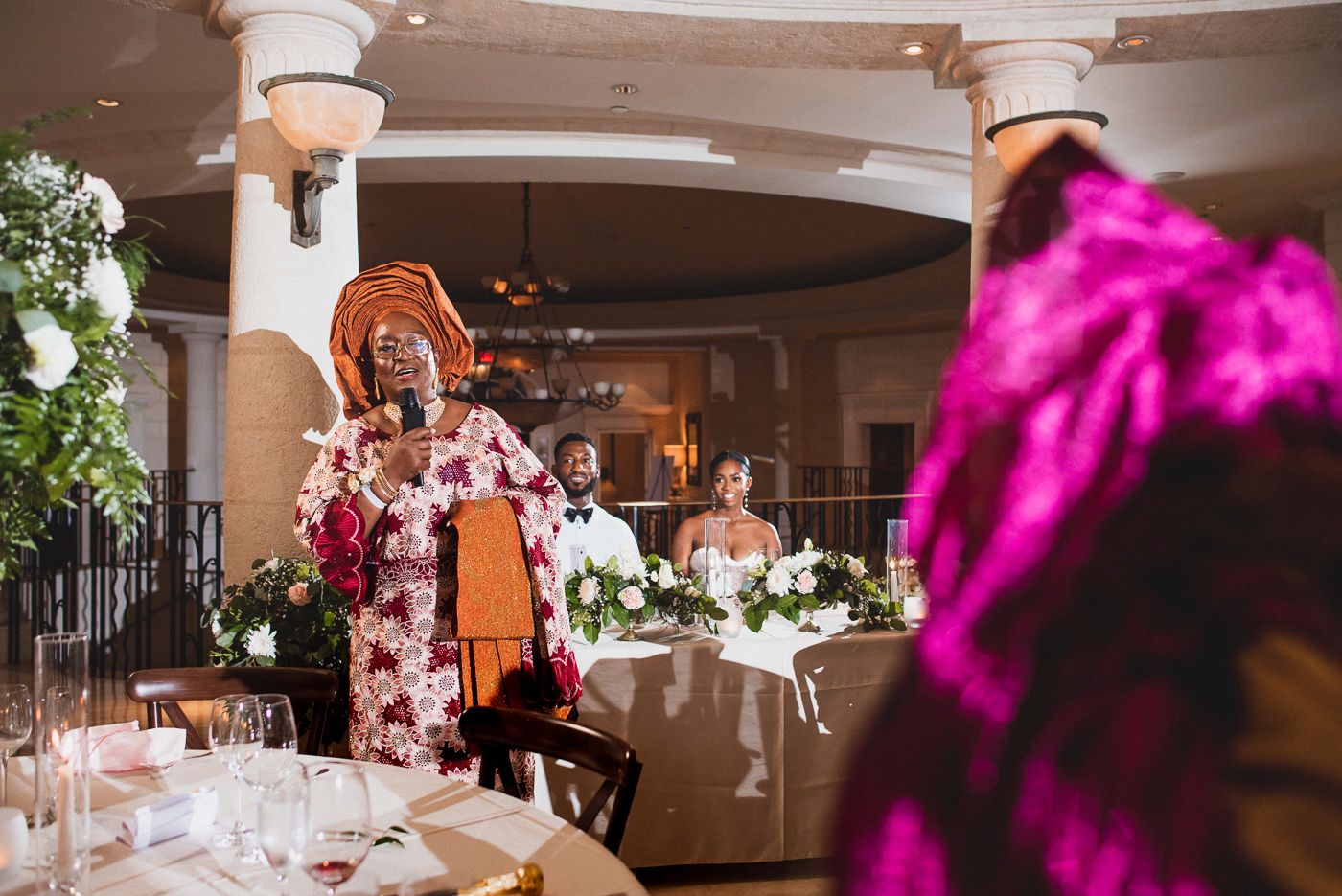 Elegant wedding venue with mood lighting, decorative columns, and floral arrangements.