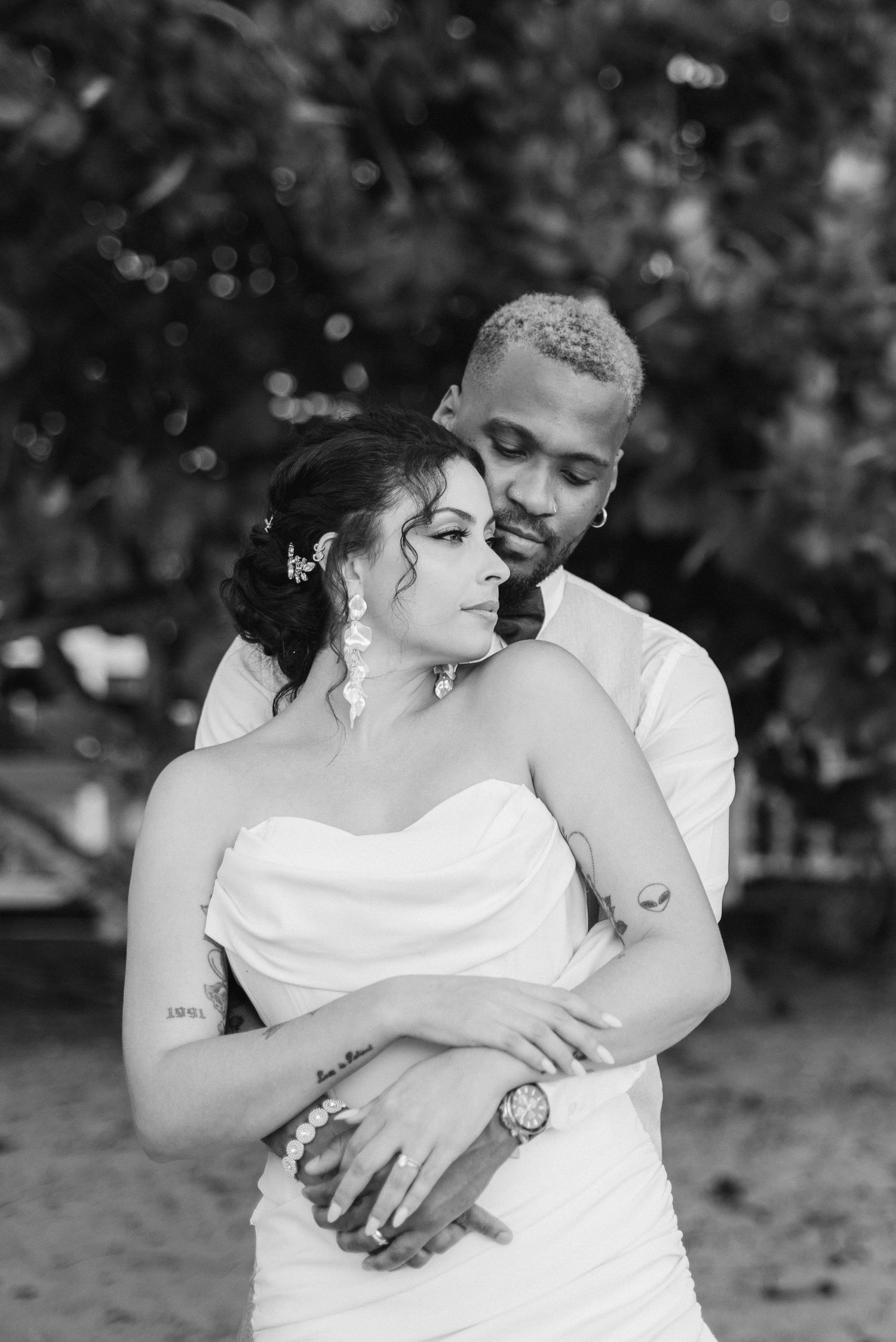 Intimate black and white portrait of newlyweds sharing a tender embrace outdoors.