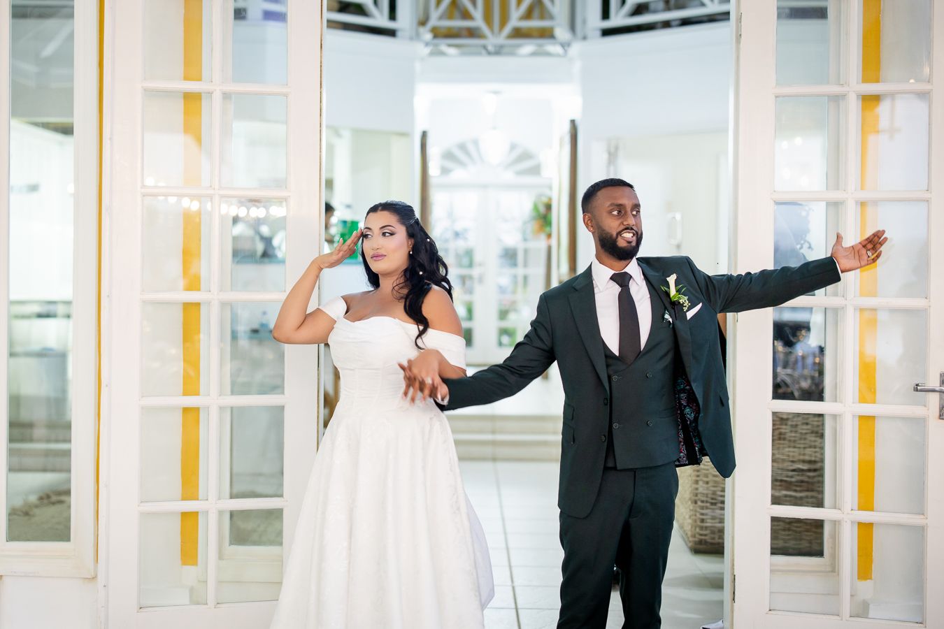 Joyful wedding celebration with guests dancing under white columns and yellow accents.