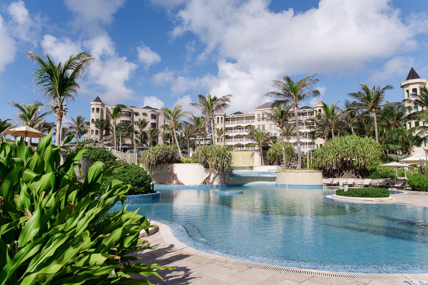 The crane resort barbados, wedding venue, with multiple swimming pools surrounded by palm trees and luxury condominiums under blue skies.