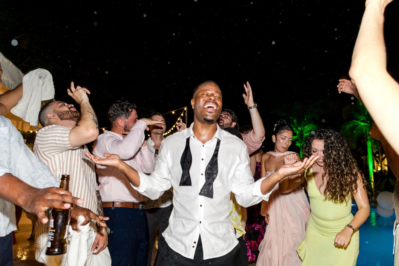 Wedding reception dance floor filled with guests dancing with their arms in the air.