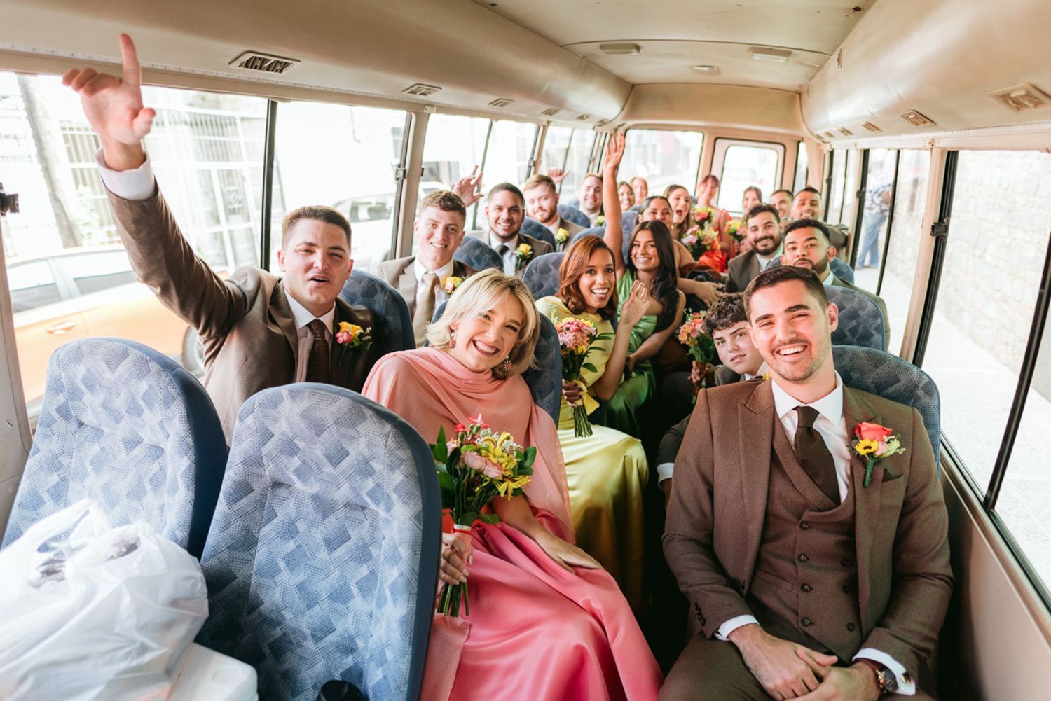 People enjoying themselves while riding on what appears to be a packed party bus or tour bus interior.
