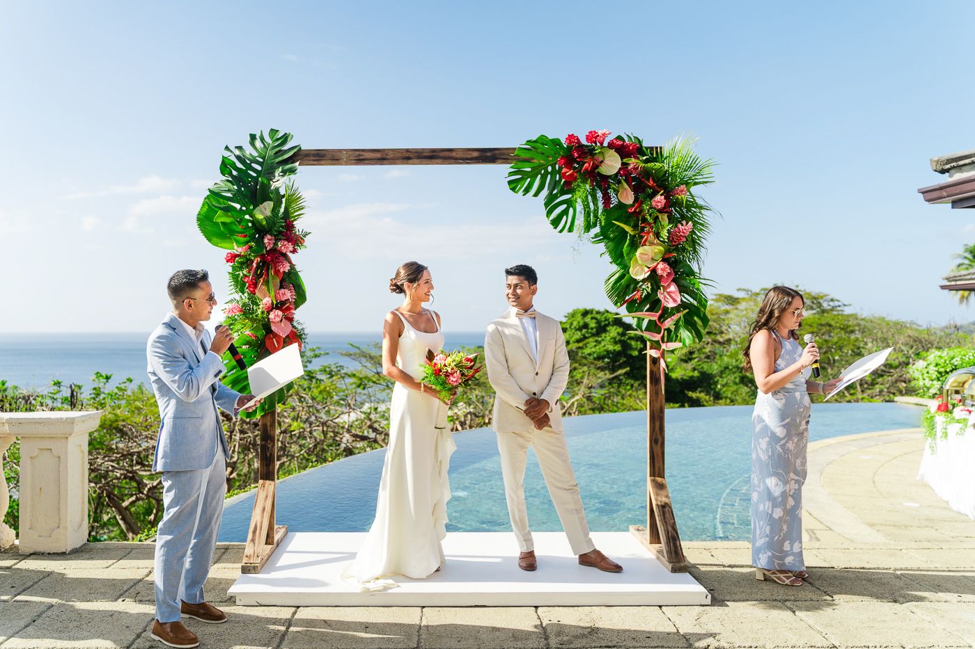 Intimate wedding ceremony under floral arch with stunning coastal views.