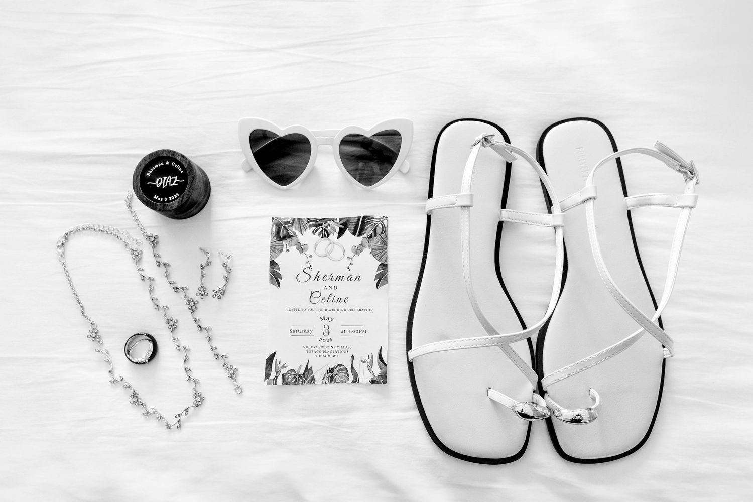 Wedding accessories and details arranged in black and white including jewelry and invitations.