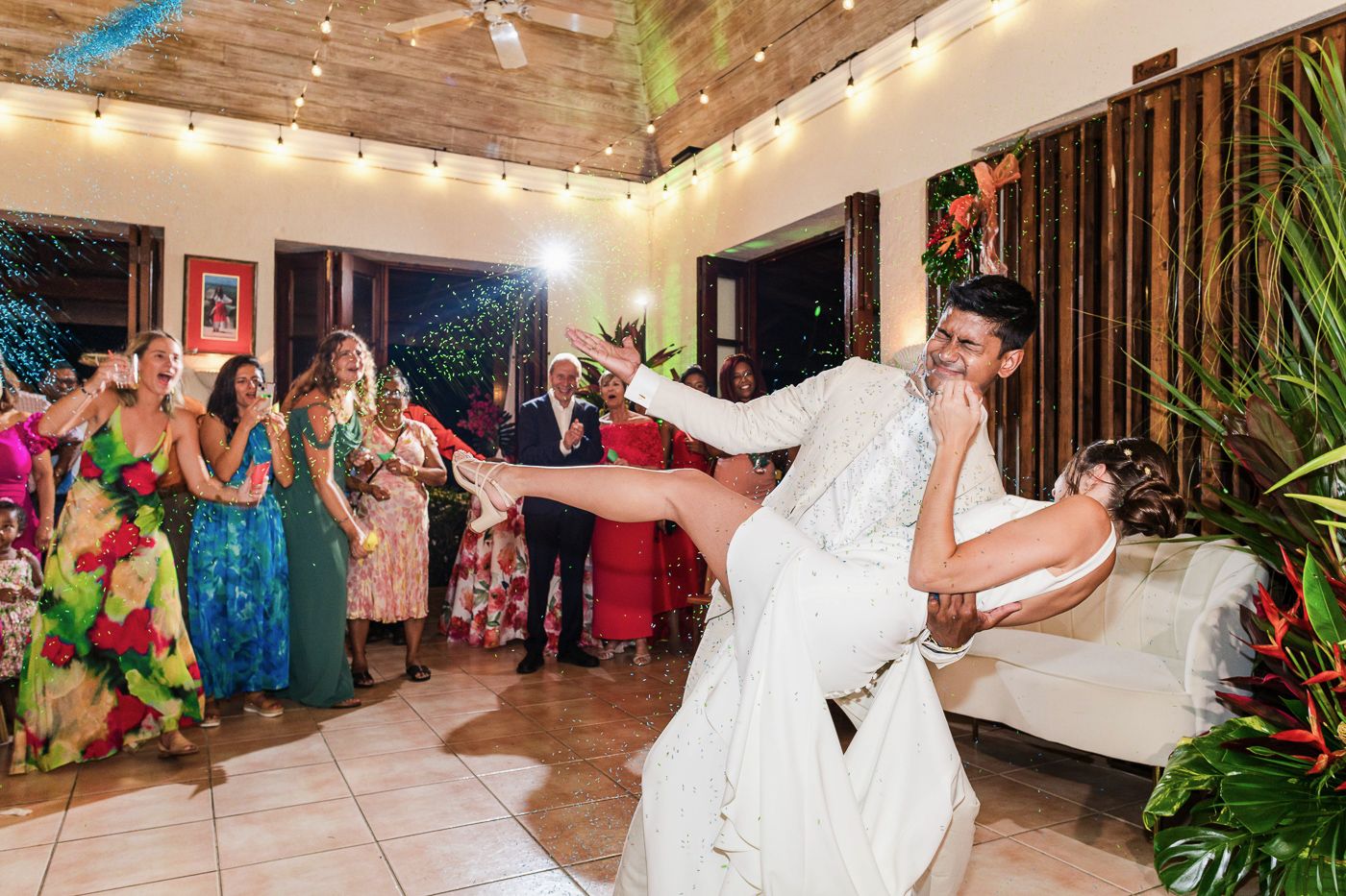Dynamic wedding reception dance photo with couple twirling on illuminated dance floor.