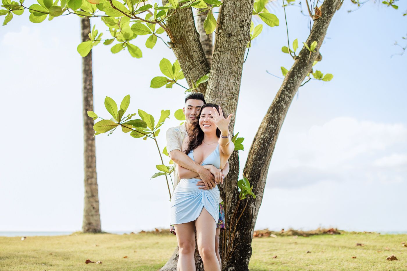 Romantic photoshoot sequence under a tree with greenery in the background.