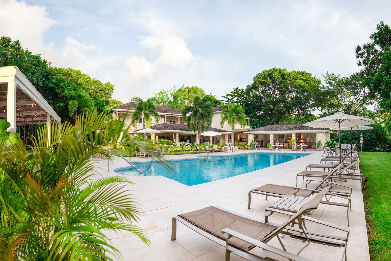 luxury Villa in Barbados, the pool area images showing lounge chairs, palm trees, and a pristine swimming pool on a sunny day.