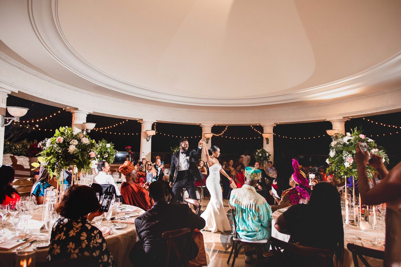 Panoramic view of an elegant wedding reception venue with string lights and white columns.