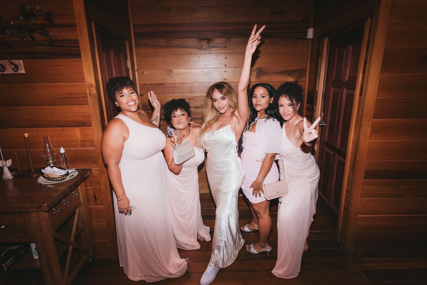 People in white outfits dance and celebrate together in a rustic wooden interior space.