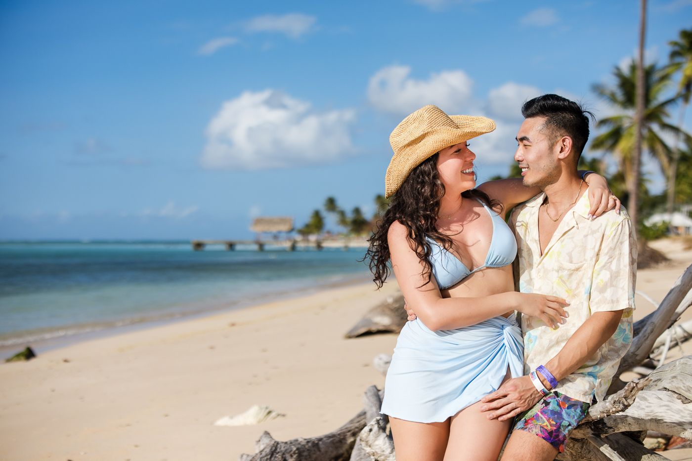 Couple sharing romantic moments on a secluded beach with crystal clear waters and swaying palms.