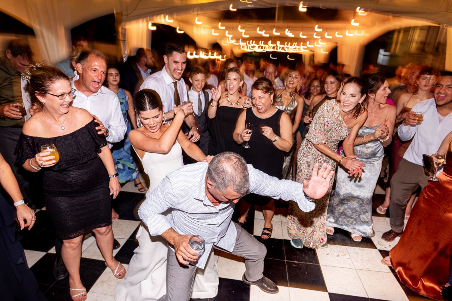 Various partygoers dance and celebrate on the dance floor at a lively reception event.
