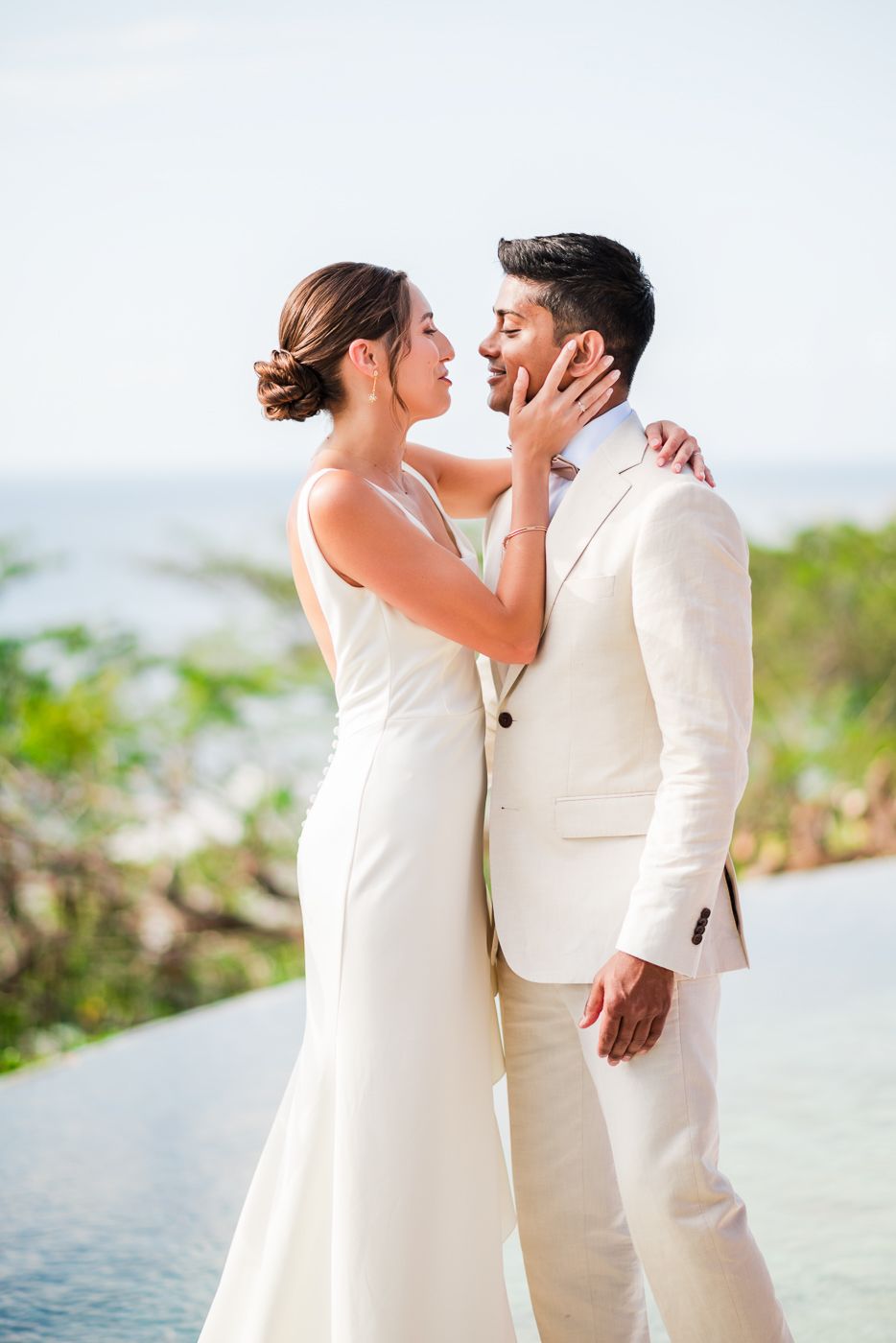 Romantic moment captured between newlyweds by infinity pool with ocean view.