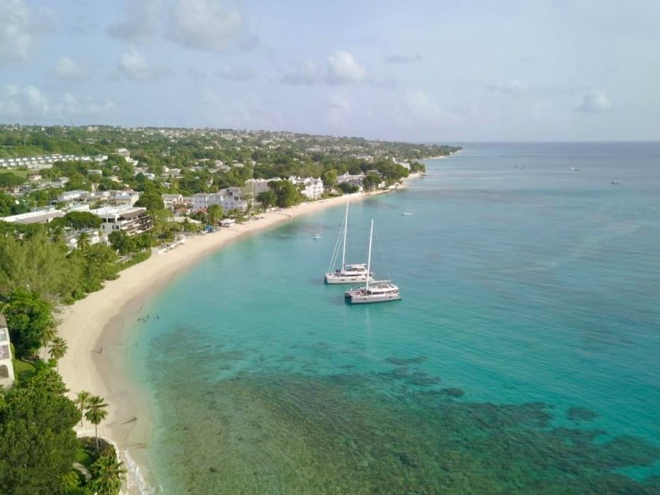 Aerial view of turquoise Caribbean waters and sandy beaches along the barbados tropical coastline dotted with boats and resorts.