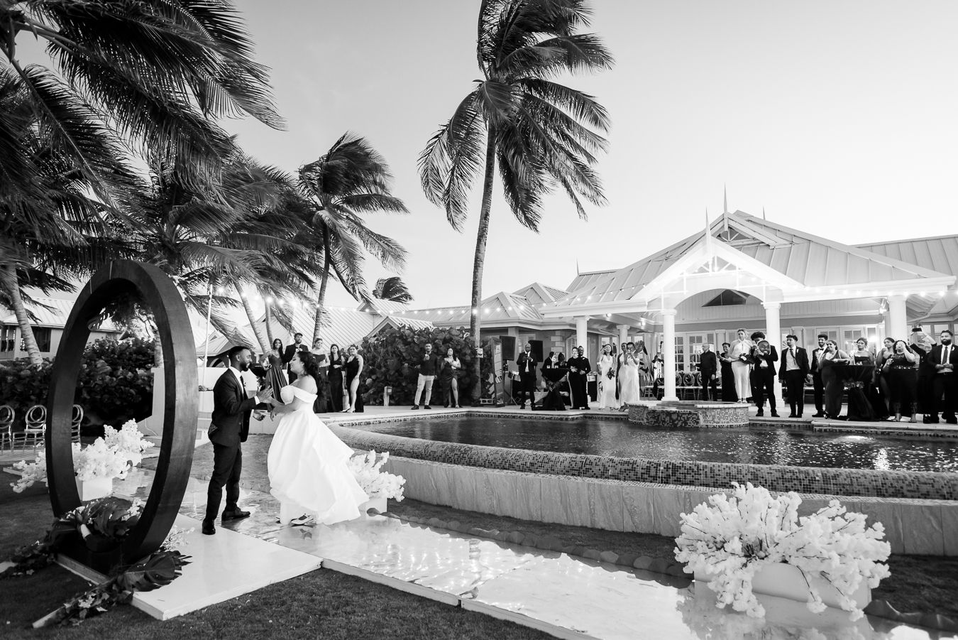 Black and white panoramic view of a beach wedding venue with palm trees and coastal landscape.