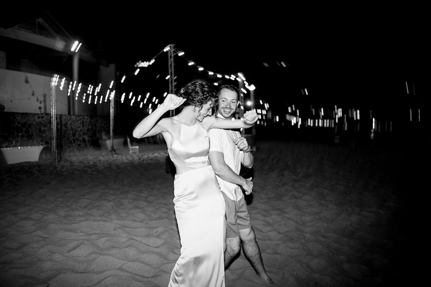 Black and white photo of couples dancing at a festive beach celebration.