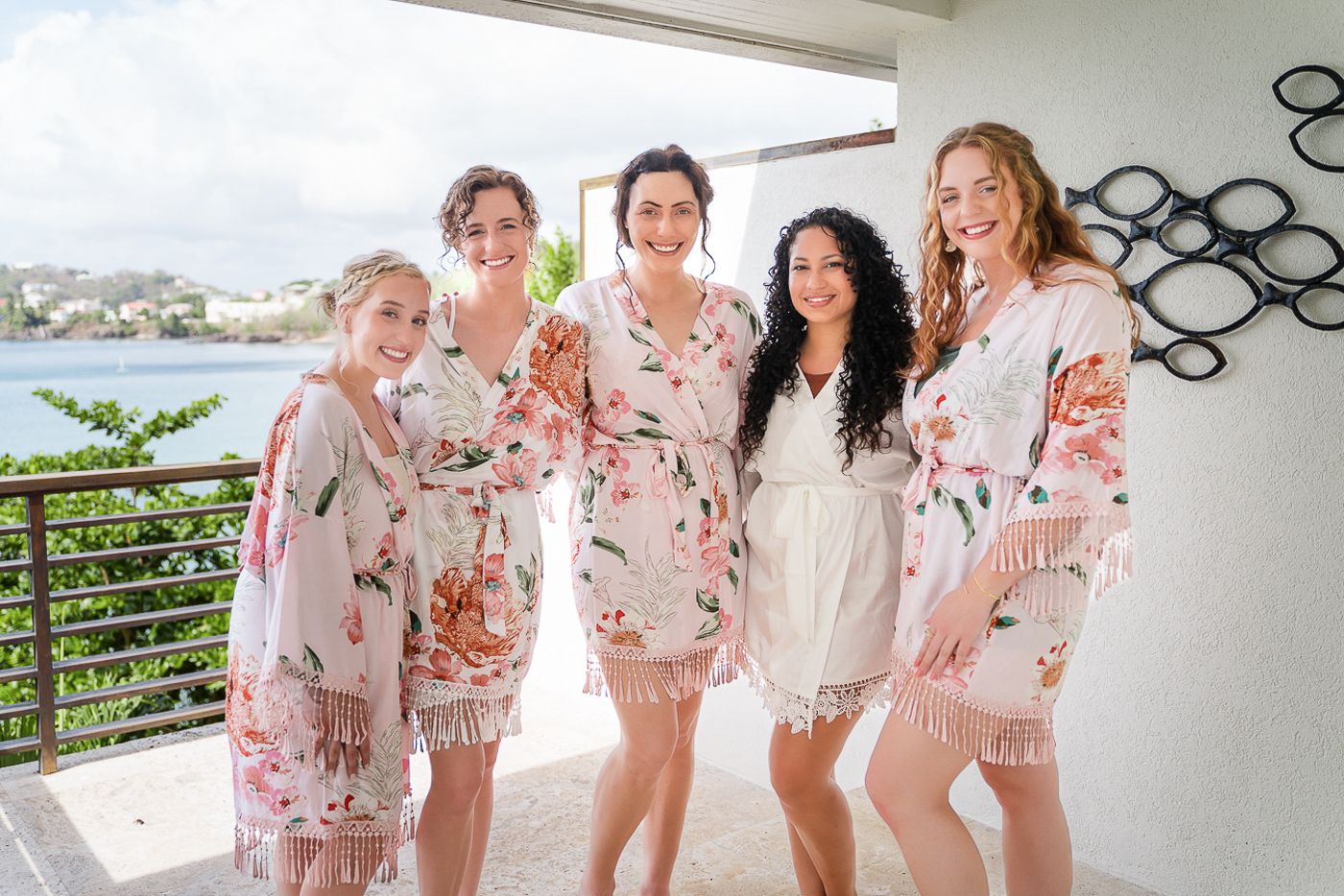 Group in pink floral robes enjoying a celebration on a sunny balcony.