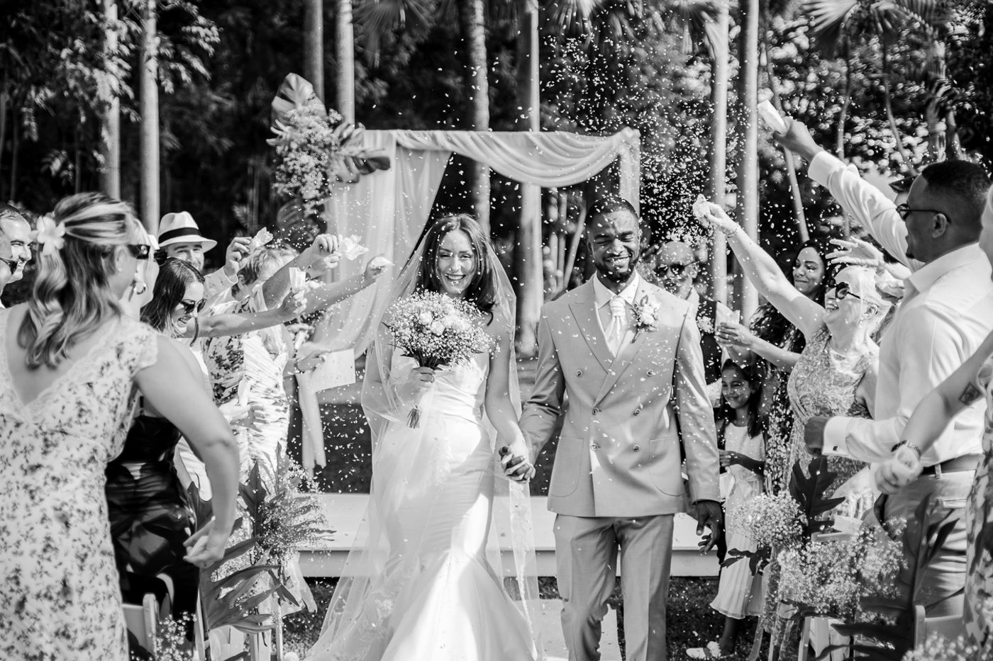 Black and white photo of wedding attendees celebrating during an emotional outdoor ceremony moment.