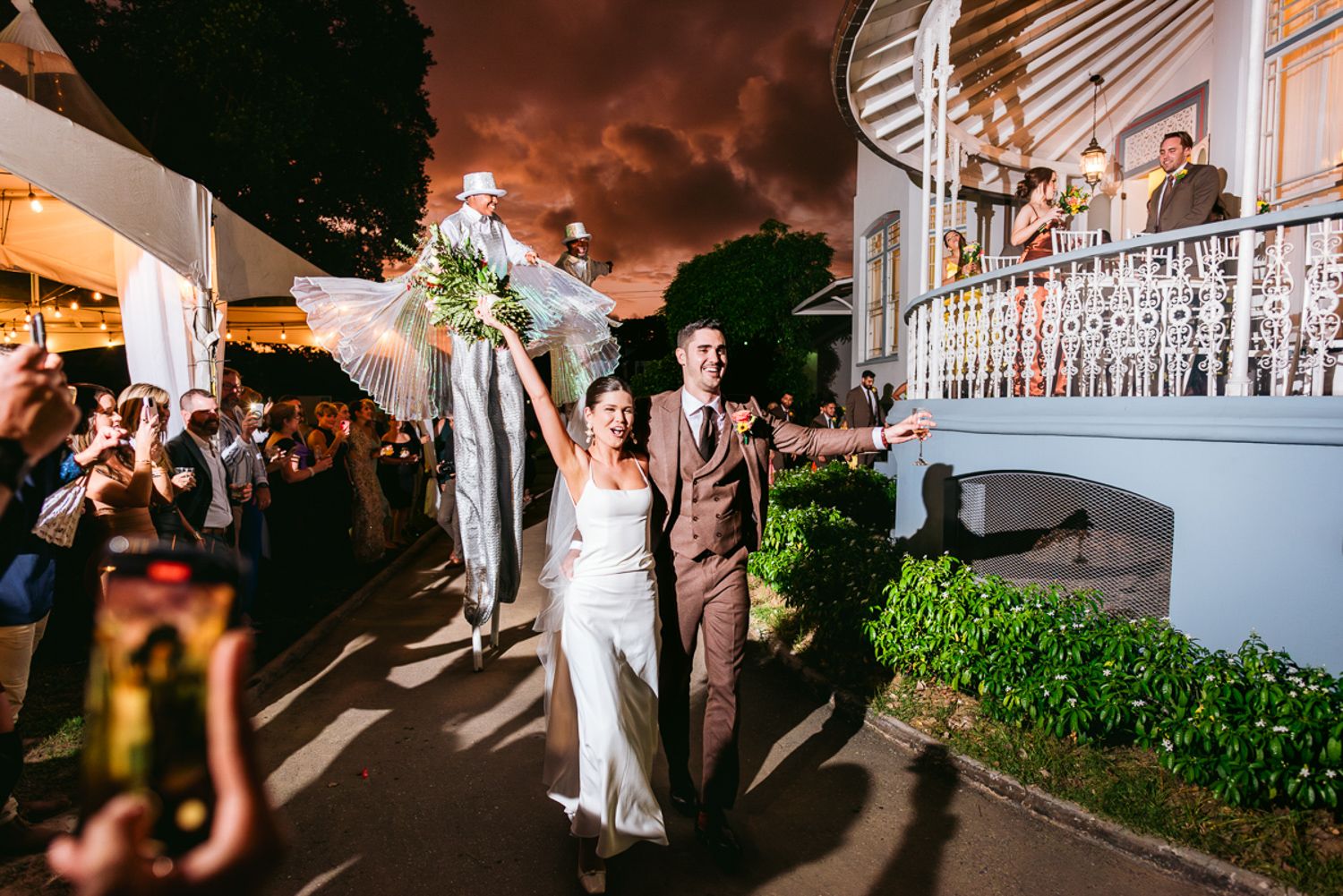 An elegant outdoor wedding reception features string lights illuminating a tented dance floor and dining area.