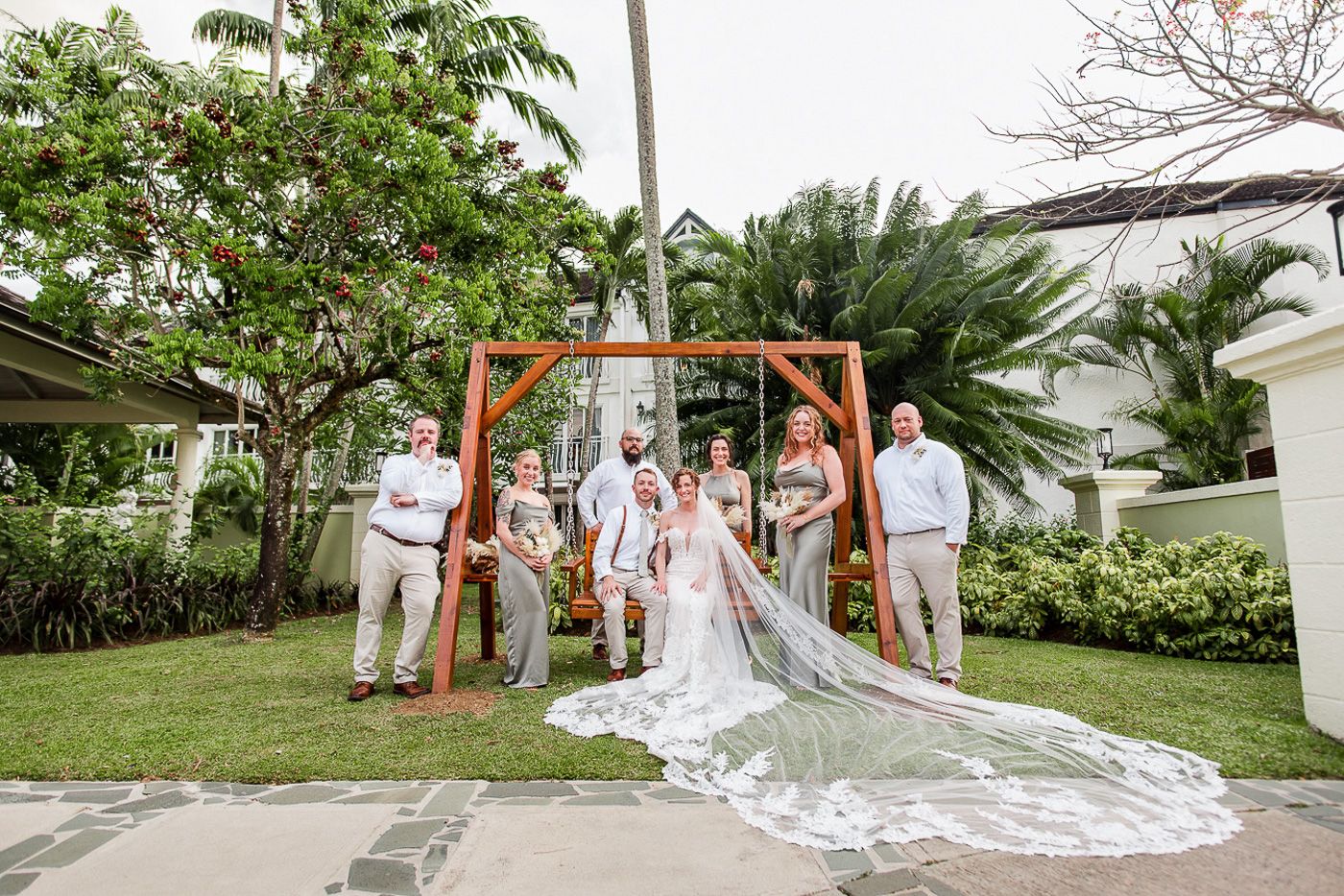 Wedding party poses together in front of palm trees and greenery.