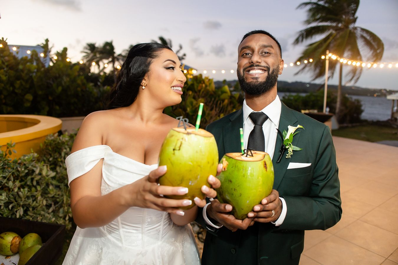 Wedding couple enjoying fresh coconut drinks at a tropical beach reception.