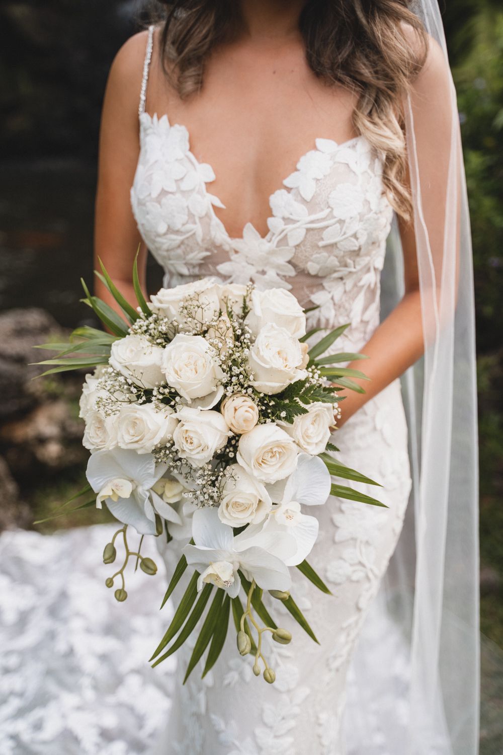Beautiful white rose and greenery wedding bouquet with flowing veil.